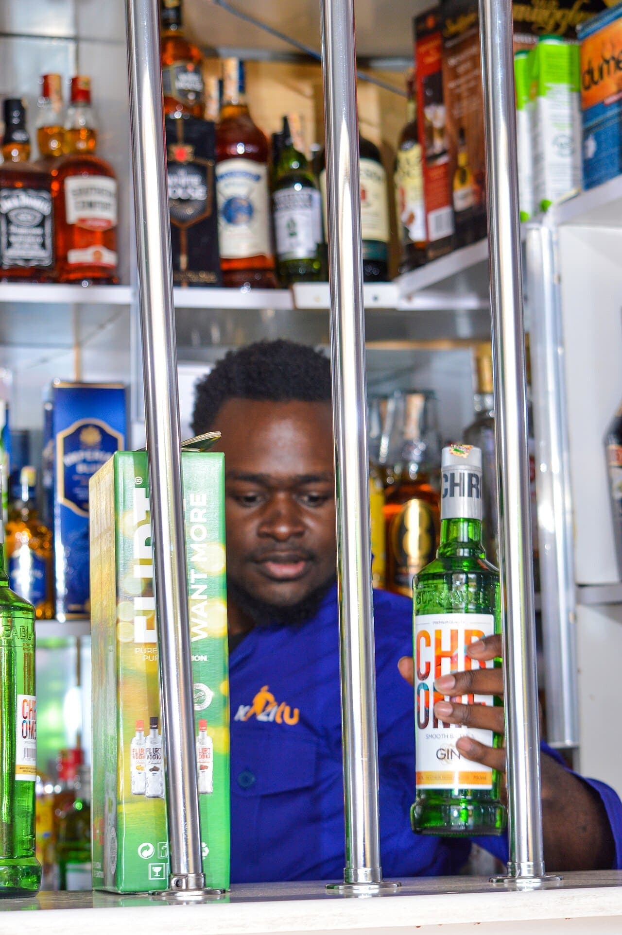 An attendant reaching for a bottle behind the counter of a Kenyan liquor store